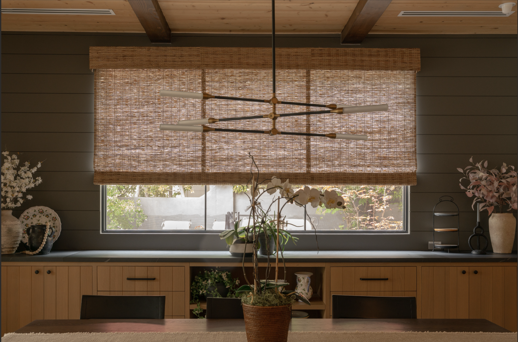 Woven shade in a modern kitchen with natural wood cabinetry and pendant lighting