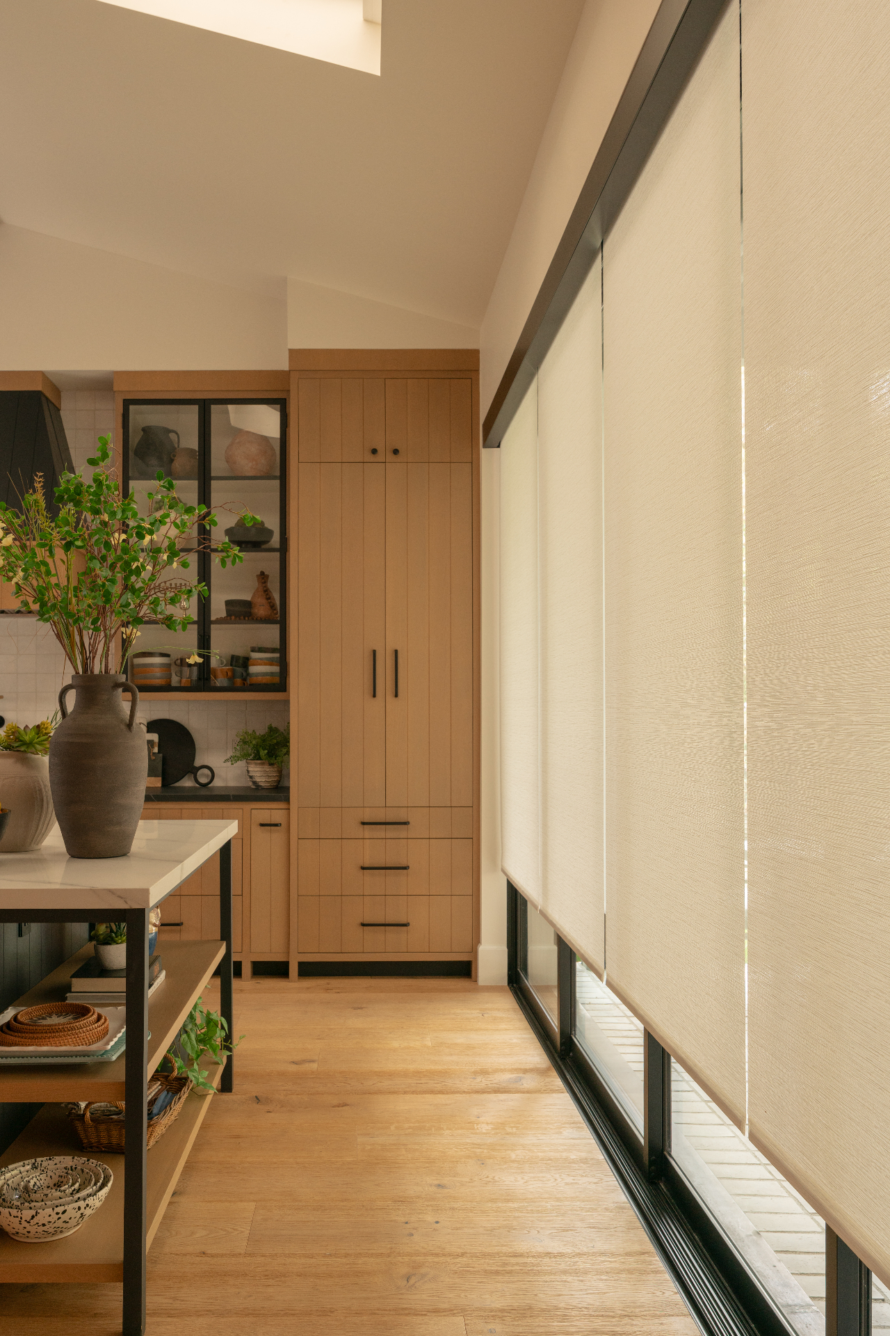 Custom roller shades along a sunlit kitchen wall