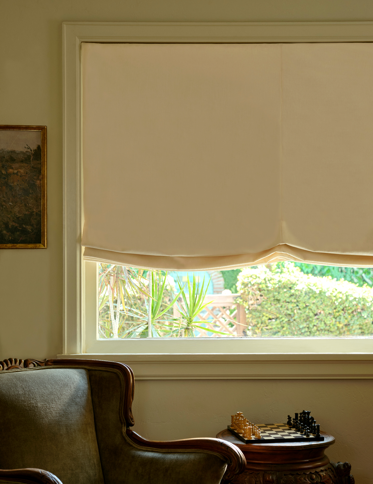 Cream Roman shade in a relaxed fold, framed by a leather armchair and chess set